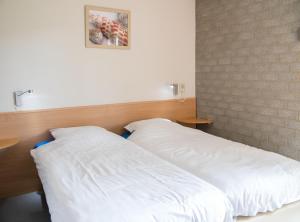 a bedroom with two white beds in it at Vakantiepark Broedershoek in Koudekerke