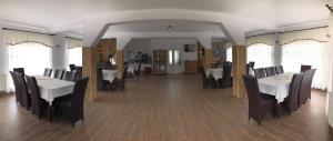 a dining room with white tables and black chairs at “Doru’ Muntelui” in Vatra Dornei