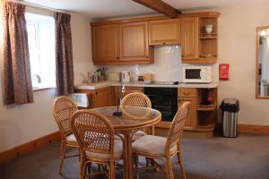 a kitchen with a table and chairs in a kitchen at Old Camms Holiday Cottages in Askrigg