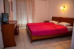 a bedroom with a bed with a red blanket at Hotel Adonis in Kriopigi