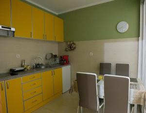 a kitchen with yellow cabinets and a table with chairs at Apartment Temple in Podgorica