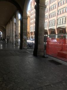 una calle vacía con edificios y una valla en Affittacamere Romina en Bolonia