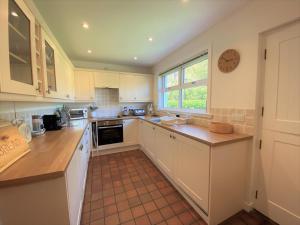 a kitchen with white cabinets and a clock on the wall at Tramway Cottages in Ellanbeich