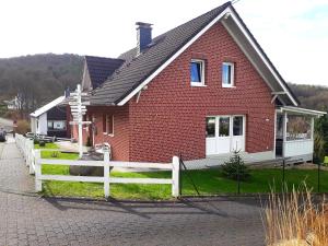 a red brick house with a white fence in front of it at Ferienwohnung Neustadt-Wied in Neustadt