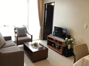un soggiorno con TV, divano e tavolo di Cebu Cozy Ocean View 1BR,17th,private beach,pool,Wifi,Mactan a Mactan