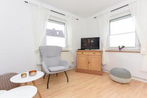 a living room with a chair and a television at Ferienhaus Nordseeliebe in Esens