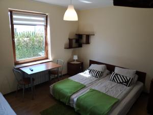 a bedroom with a bed and a desk and a window at Rivabell in Ostrowo