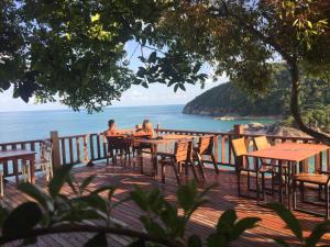 two people sitting at tables on a deck looking at the ocean at Plaa's Thansadet Resort in Than Sadet Beach