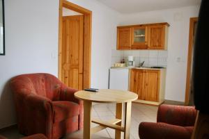 a living room with a table and a chair and a kitchen at Wagner Panzió in Cserszegtomaj