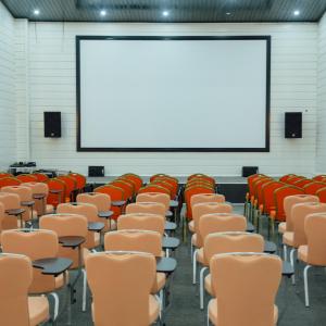 une salle de conférence vide avec des chaises et un écran dans l'établissement RIVER INN RESORT AND SPA, à Nabran