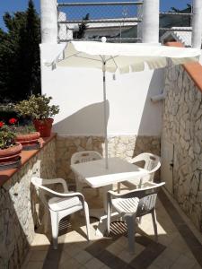 einen weißen Tisch und Stühle sowie einen Regenschirm auf einer Terrasse in der Unterkunft Case vacanze Vignola in Peschici
