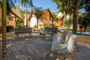 two chairs and a bench in front of a house at Ody Park Resort Hotel in Iguaraçu