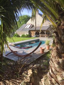 a hammock in front of a house with a pool at La petite Hautière Maison 2 personnes Plouer sur Rance avec piscine in Plouër-sur-Rance