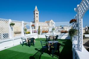 a patio with chairs on a green lawn at White House in Trani