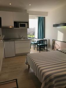 una camera da letto con un letto e una cucina con un tavolo di Studio piscine et vue mer a Trévou-Tréguignec