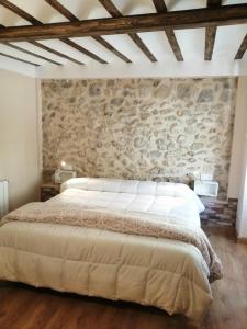 1 dormitorio con 1 cama grande en una pared de piedra en Habitacion tienda de felipe EL DESPACHO, en Pontones