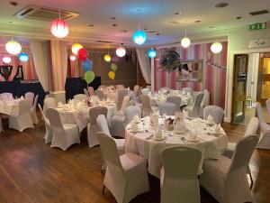 una sala de banquetes con mesas blancas, sillas y luces en The Corralea Court, en Tuam