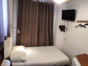 Habitación pequeña con cama y TV. en Hotel Schroder, en Ámsterdam