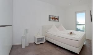 ein weißes Schlafzimmer mit einem weißen Bett und einem Fenster in der Unterkunft Exklusive Ferienwohnung mit Blick auf den Yachthafen in Peenemünde