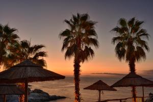 a group of palm trees and umbrellas on a beach at Arbatax Park Resort - Ville del Parco in Àrbatax