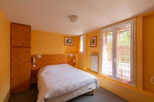 ein Schlafzimmer mit gelben Wänden, einem Bett und einem Fenster in der Unterkunft Hotel Bellevue in Chambon-sur-Lac