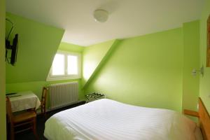 ein grünes Schlafzimmer mit einem Bett und einem Fenster in der Unterkunft Hotel Bellevue in Chambon-sur-Lac