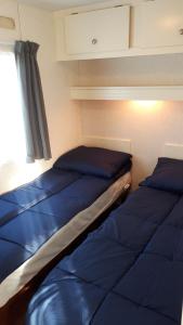 2 Betten in einem kleinen Zimmer mit Fenster in der Unterkunft AMELAND - Ballum: Stacaravan Chalet (incl. fietsen) bij strand en zee in Ballum