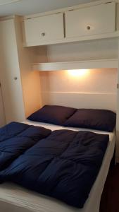 a bedroom with two beds and a light on the wall at AMELAND - Ballum: Stacaravan Chalet (incl. fietsen) bij strand en zee in Ballum