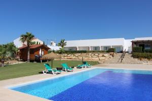a swimming pool with chairs and a house at Guesthouse Quinta Saleiro in Olhão