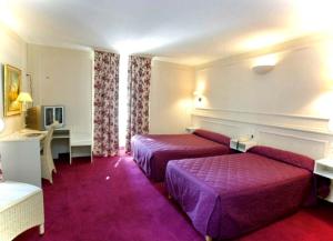 a hotel room with two beds and a desk at Le Grand Hôtel in Souillac