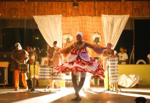Cana Brava All Inclusive Resort في أولايفينزا: رجل بلبس احمر وبيض يرقص على المسرح