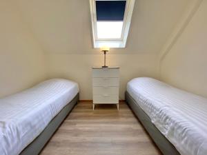 two beds in a room with a window and a dresser at Zandvoort Central Apartment in Zandvoort
