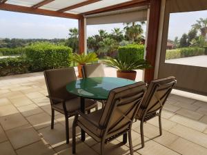 une table et des chaises en verre sur la terrasse dans l'établissement Guesthouse Quinta Saleiro, à Olhão