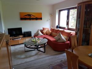 ein Wohnzimmer mit einem roten Sofa und einem Tisch in der Unterkunft Ferienwohnung am Mozarthügel in Warstein