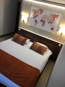 a bedroom with a bed with two pillows and a map at Kyriad Montpellier Nord Parc Euromédecine in Saint-Clément-de-Rivière +33 photos
