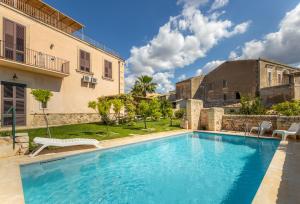 a swimming pool in a yard next to a building at Villa Rosaria Rooms in Noto