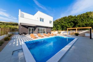 a villa with a swimming pool in front of a house at Villa Belveder in Pag