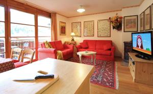 salon z czerwonymi kanapami i telewizorem w obiekcie Family Apartment FUCHS Bad Kleinkirchheim w mieście Bad Kleinkirchheim