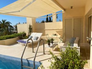 un patio con una sombrilla blanca y una piscina en Luxury Apartment Penthouse in Sotogrande Paseo del Mar, en San Roque