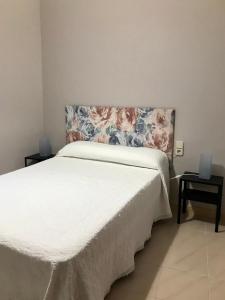 a bedroom with a white bed with a floral headboard at Casa de la Abuela in Fabero