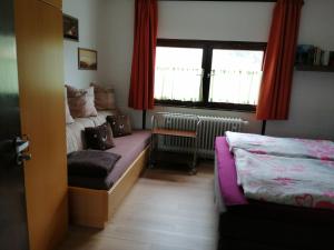 een slaapkamer met 2 bedden en een raam met rode gordijnen bij 2 Raum Ferienwohnung Sonnenschein in Sankt Englmar