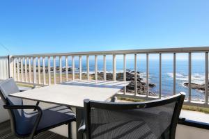 een tafel en stoelen op een balkon met uitzicht op de oceaan bij La Petite Sirène in Quiberon