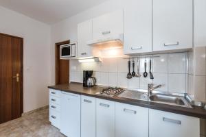 a kitchen with white cabinets and a sink at Apartments Mikanović in Crikvenica
