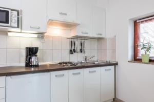 a kitchen with white cabinets and a sink at Apartments Mikanović in Crikvenica
