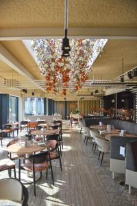 a restaurant with tables and chairs and a chandelier at Fletcher Wellness-Hotel Kamperduinen in Kamperland