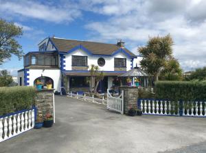 una casa azul y blanca con una valla blanca en Barkers Accommodation, en Spanish Point