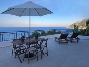um pátio com uma mesa, cadeiras e um guarda-sol em Villa Astraea Kyra Panagia em Kyra Panagia