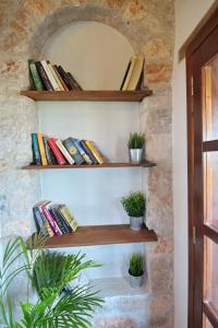 un mur avec des étagères avec des livres et des plantes en pot dans l'établissement Angel Sunset suite, à Patitiri