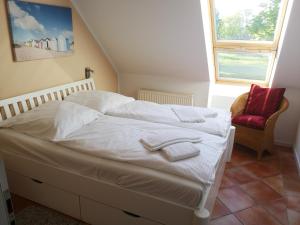 SeedorfにあるFerienwohnung mit Südbalkonのベッドルーム1室(白いシーツと赤い椅子付きのベッド1台付)