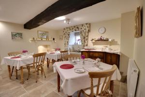 a dining room with tables with white tablecloths at Millstream Cottage B & B in Dunster